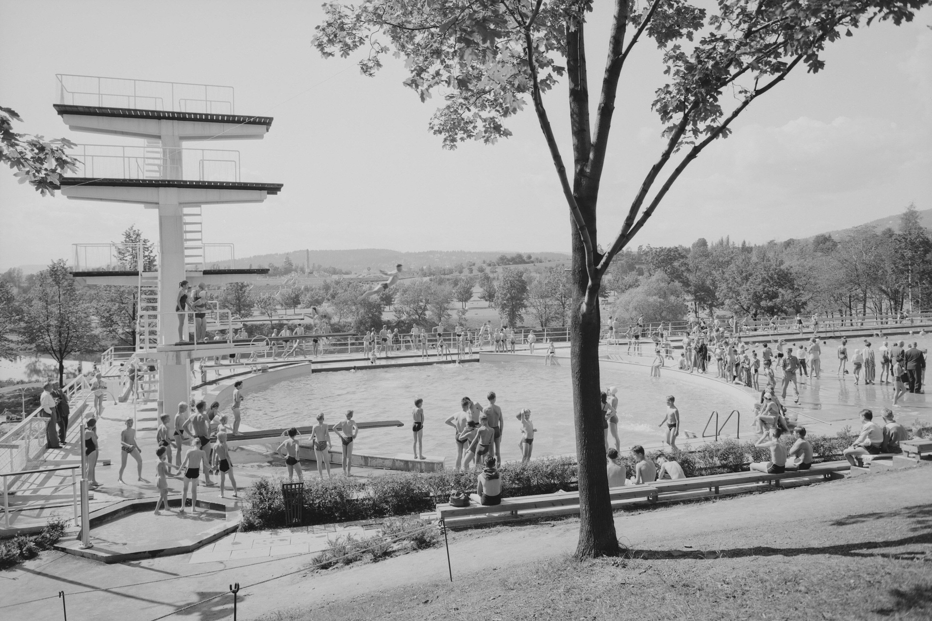 Frognerbadet på åpningsåret 1956 – stupetårnet reiser seg over det ovale bassenget mens badegjester samler seg langs kanten.